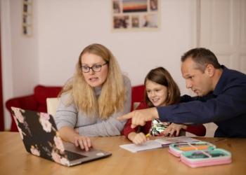 A woman and a man helping a child with schoolwork on a laptop