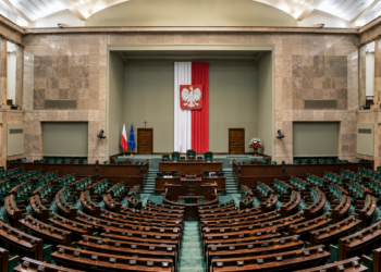 AI-generated editorial reconstruction of an empty Polish parliamentary chamber resembling the Sejm; not an authentic photograph of the 22 October 2026 tax-reform vote