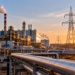 AI-generated conceptual illustration of an industrial plant and electricity transmission lines at sunset, not an identified factory or facility involved in the Visegrád EU funding talks
